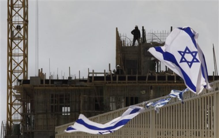 Construction workers work on a new housing development, as an Israeli flag flies in the foreground, in the Jewish neighborhood of Har Homa, in east Jerusalem, Thursday, April 22, 2010. Aides to Israel's prime minister said Thursday that he has officially rejected President Barack Obama's demand to suspend all construction in contested east Jerusalem, a move that threatens to entrench a year-old deadlock in Israeli-Palestinian peacemaking. (AP Photo/Sebastian Scheiner)